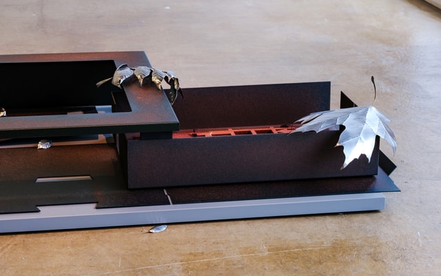A metal floor sculpture evoking an office desk scattered with fallen leaves.